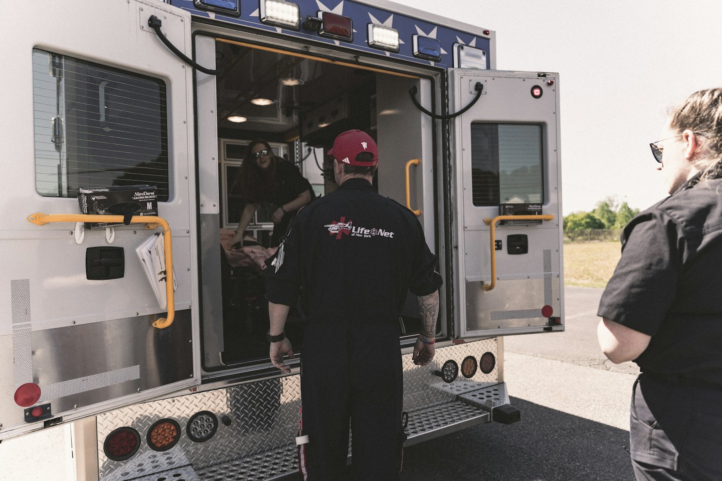 Rettungssanitäter versorgen einen Patienten in einem offenen Krankenwagen.